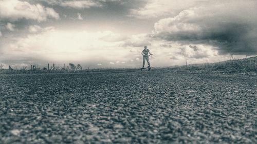 Silhouette of woman standing on landscape against cloudy sky