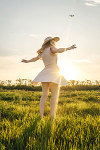 Young woman with arms outstretched standing on grassy land