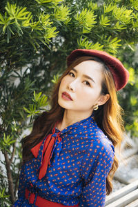 Portrait of smiling young woman standing against tree