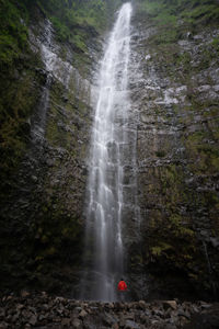 Person standing against waterfall in forest