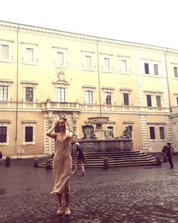 Full length of woman standing on street against building