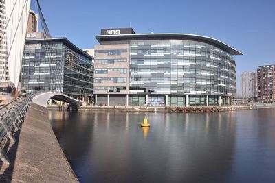 Bridge over river by buildings against sky in city