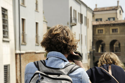 Rear view of friends on street against buildings in city