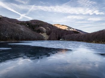 Scenic view of frozen lake by mountains against sky