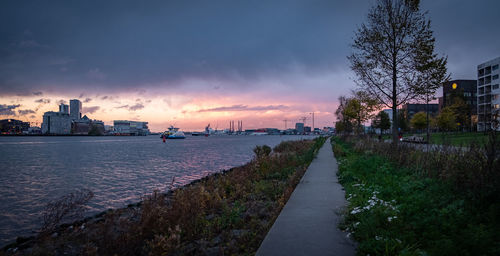 River amidst buildings against sky at sunset