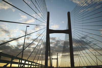 Low angle view of suspension bridge against cloudy sky