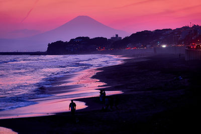 Silhouette people on beach against sky during sunset