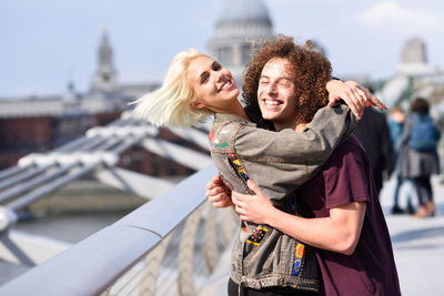 Portrait of happy woman embracing man on footbridge