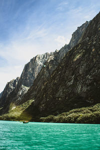 Tiny boat floating in a big lake surrounded by mountains 