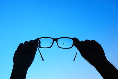 Close-up of hands against clear blue sky