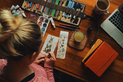 Directly above shot of woman painting easter bunny on paper