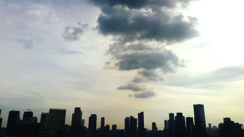 Low angle view of skyscrapers against cloudy sky