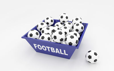 Close-up of soccer balls in purple container with football text over white background