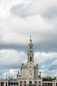 Low angle view of bell tower against cloudy sky