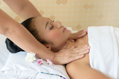 Cropped hands of masseuse giving massage to young woman relaxing at spa