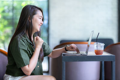 Young woman using mobile phone while sitting at home