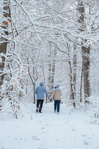 Rear view of woman walking on snow covered field