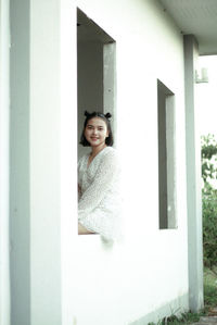 Portrait of young woman looking through window