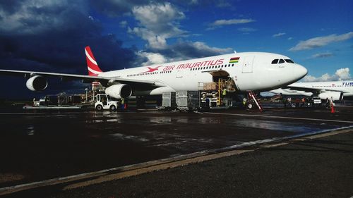 Airplane on airport runway against sky