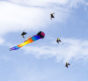 Low angle view of kites flying against sky