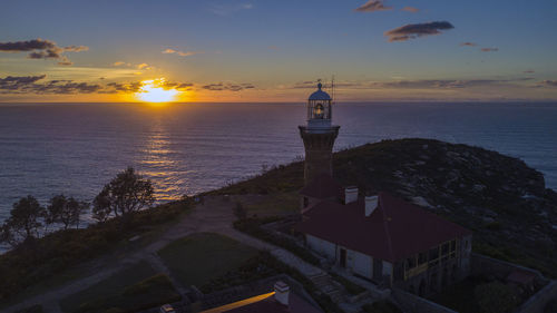 High angle view of lighthouse at seaside during sunset