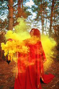 Woman standing by cross against trees