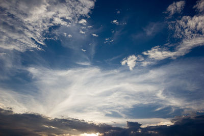 Low angle view of sunlight streaming through clouds