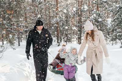 Cheerful family on a weekend rides a sleigh in a snowy forest. high quality photo