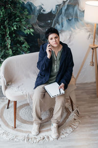 Full length of young woman sitting on chair