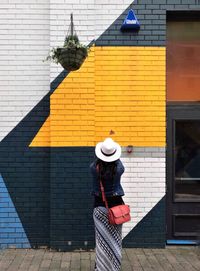 Rear view of woman standing against building