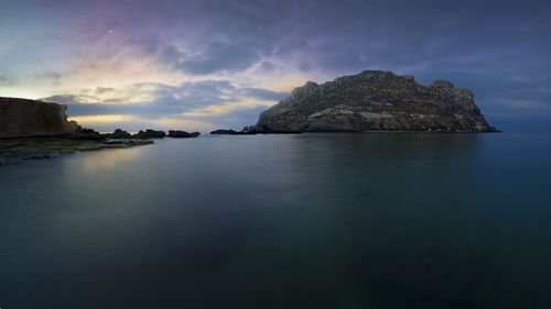 Rock formation in sea against sky