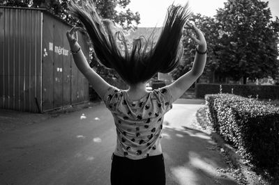 Rear view of woman tossing hair outdoors