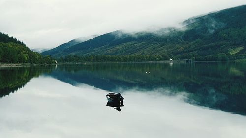 Scenic view of lake by mountains against sky