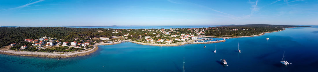 High angle view of city by sea against blue sky