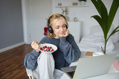 Portrait of young woman using laptop at home