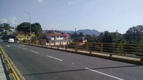 Road by buildings against clear sky