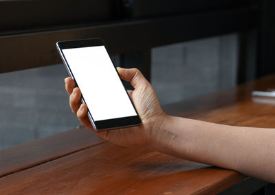 Hand holding smart phone on table