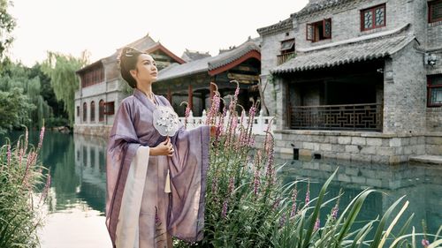 Portrait of young woman standing against building