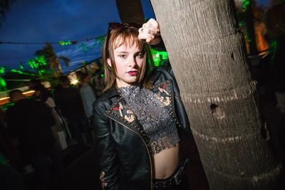 Portrait of woman standing on tree trunk