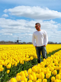 Full length of man with yellow flowers on field