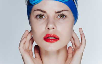 Close-up of woman applying make-up against white background