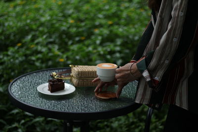 Woman holding coffee cup and saucer on table