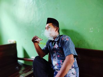 Man holding cigarette while sitting outdoors