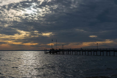 Pier over sea against sky during sunset