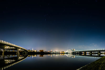 Illuminated bridge over river against sky at night