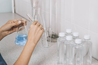 Women hands in laboratory examines quality of water, glass tube filled, blue chemical liquid, lab