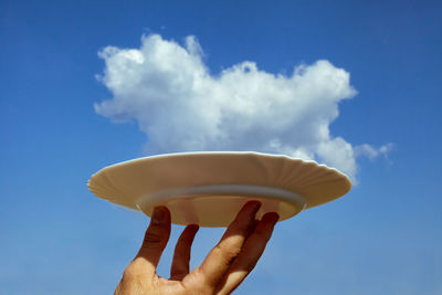 Person holding ice cream against blue sky