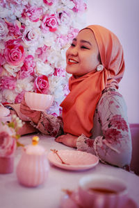 Portrait of smiling young woman sitting on table