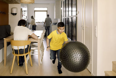 Pre-adolescent boy playing with fitness ball at home