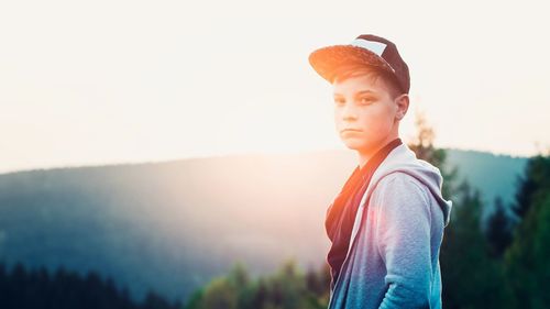 Young woman standing against clear sky during sunset